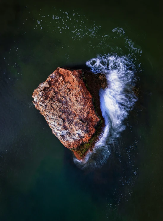 an aerial view of the ocean and a large rock