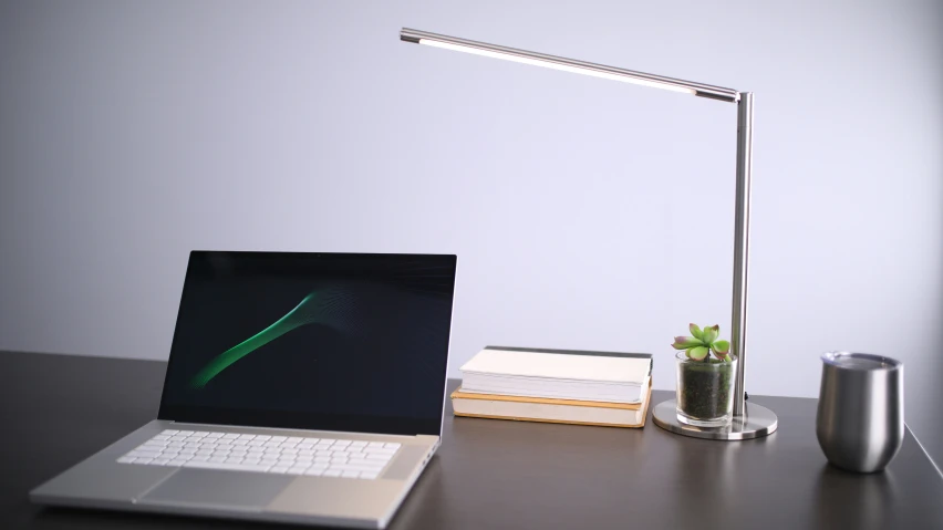 a laptop, book and lamp are on a desk