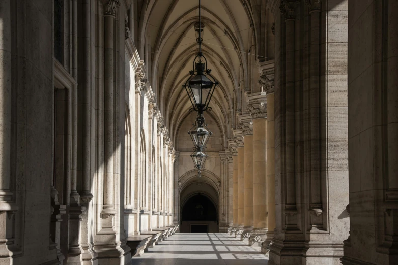 the corridor in the cathedral has columns and lights hanging