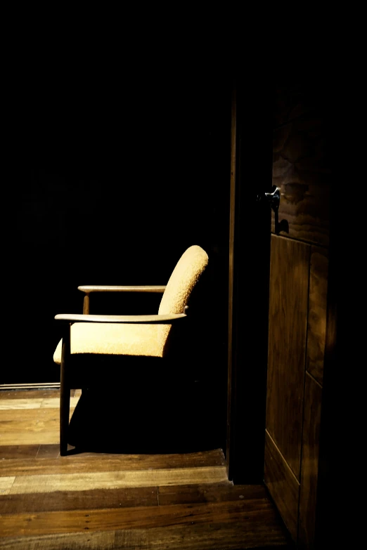 chair at open door in dark room with wood floor