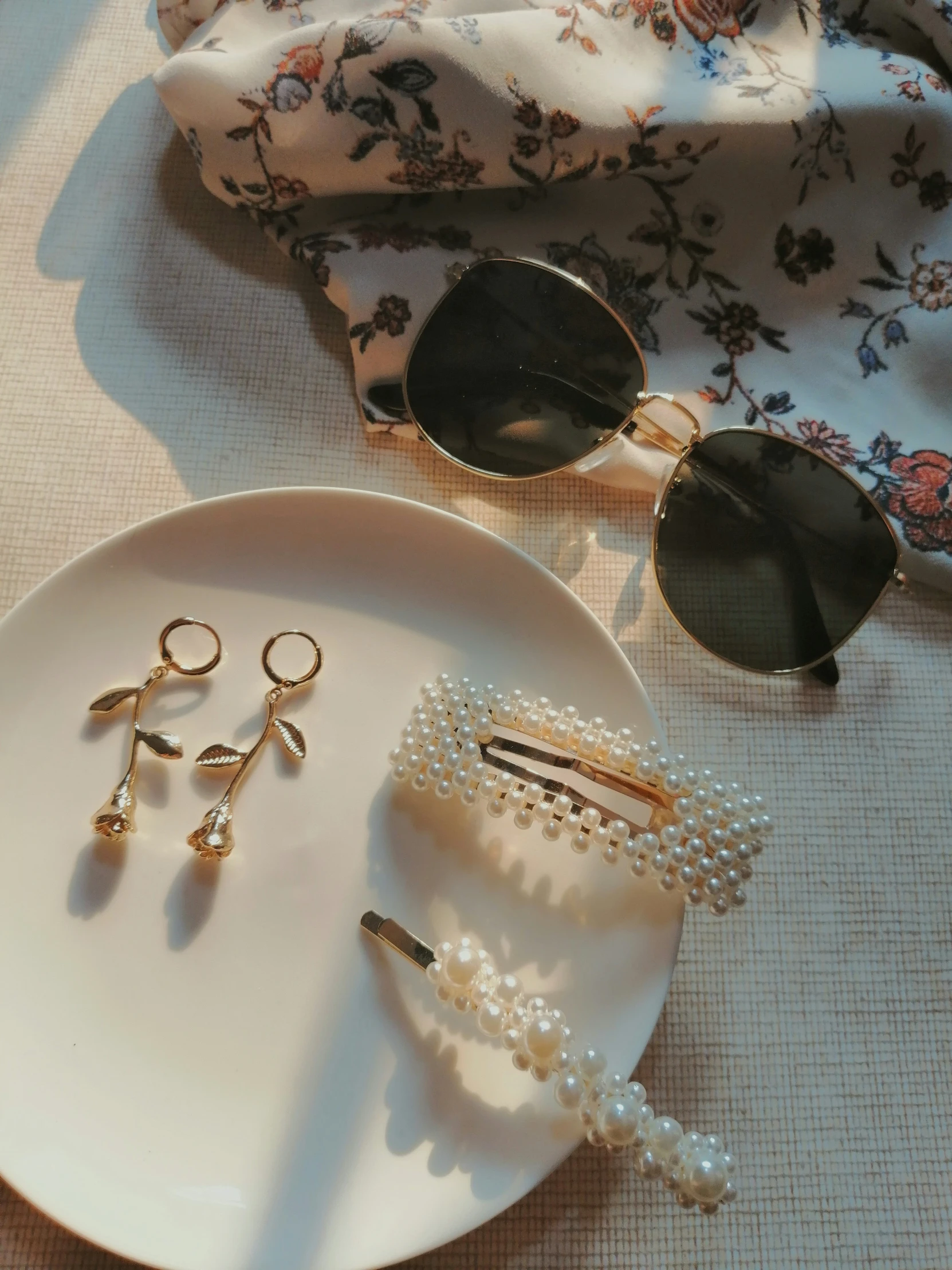 a pair of sunglasses on a plate with pearls and ear clips