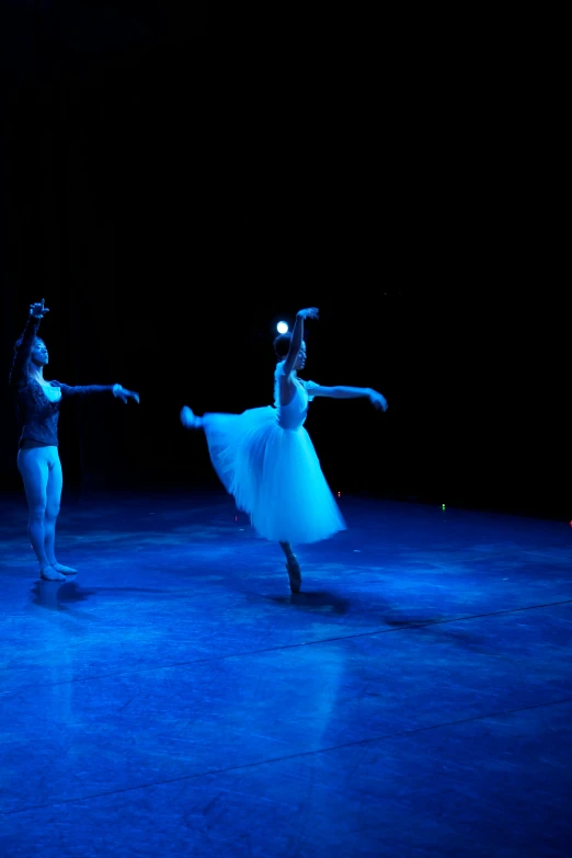 the ballerinas perform on a blue lighted floor