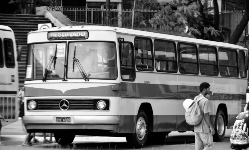 a bus is stopped at a stop with people near by