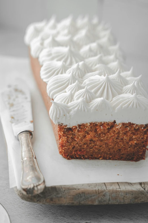 carrot cake with white frosting sitting on a  board