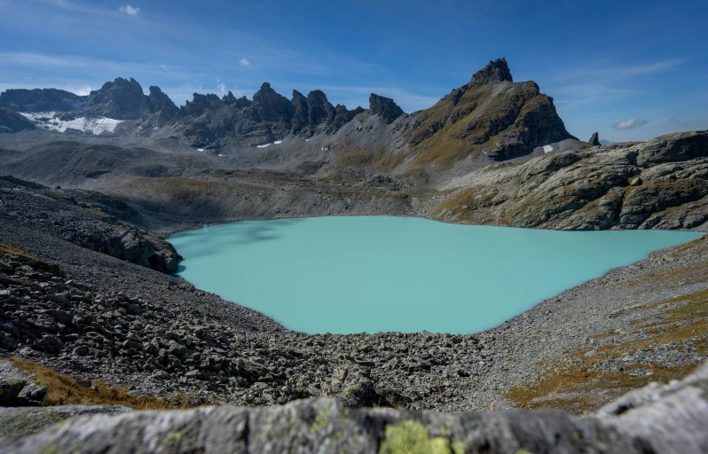 a mountain scene with a turquoise pond surrounded by mountains