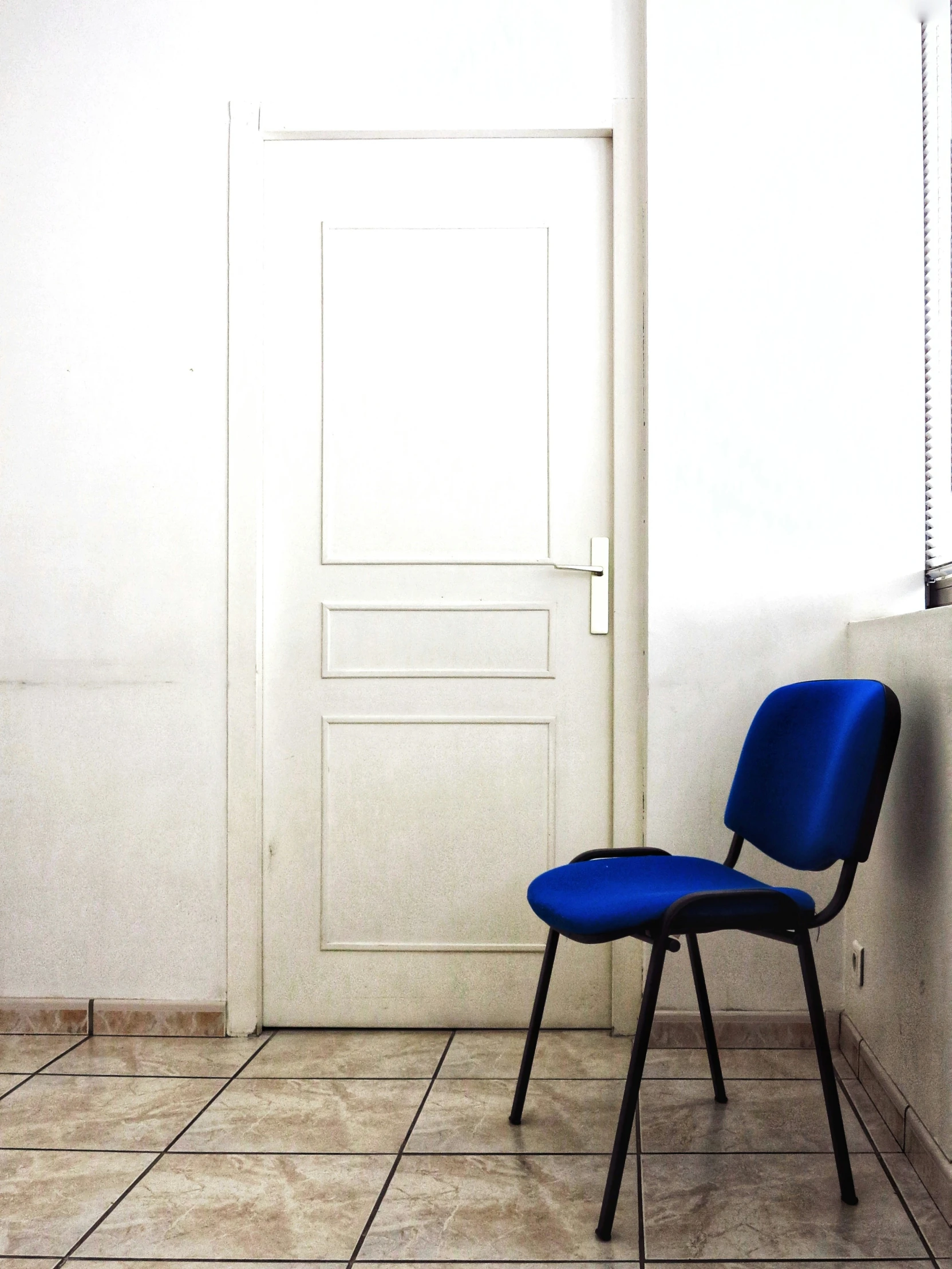 blue chair on the tile floor in front of a white door