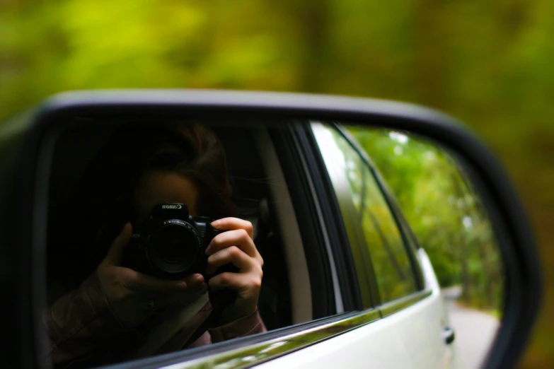 a woman in car rear view mirror holding up her camera