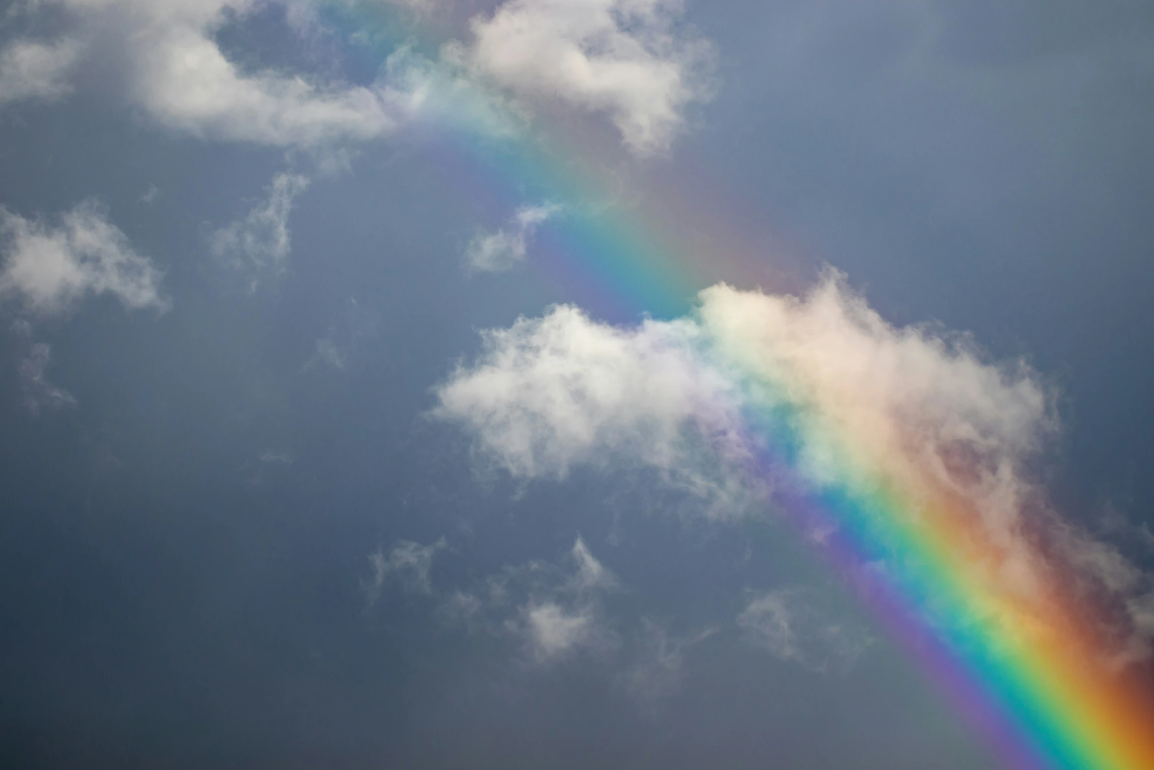 a rainbow appears brightly in the cloudy sky