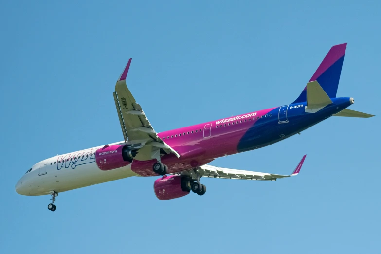 a pink and blue airplane is flying through the sky