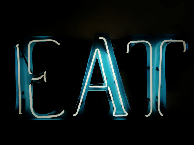 a neon sign for eat in the middle of a wall