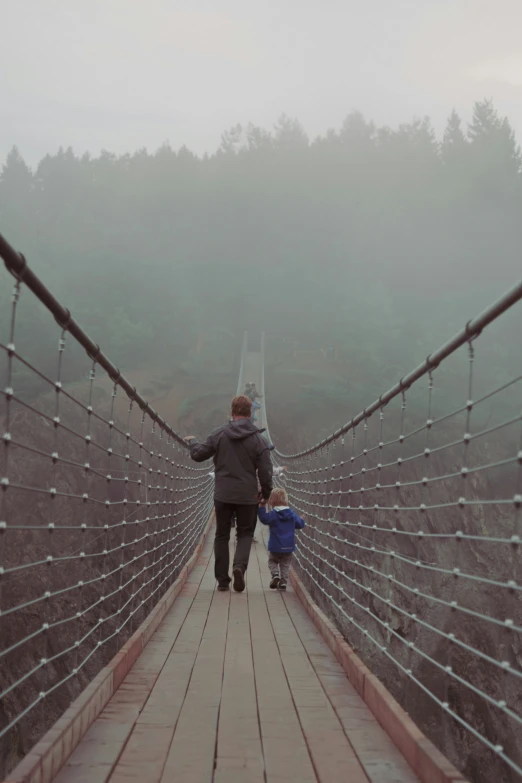 a man and a small child walking across a bridge