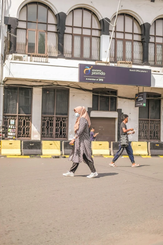 two women walk down the street, one is carrying her cell phone