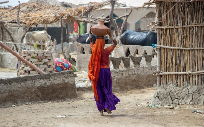 a lady carrying a large bowl on her head walking