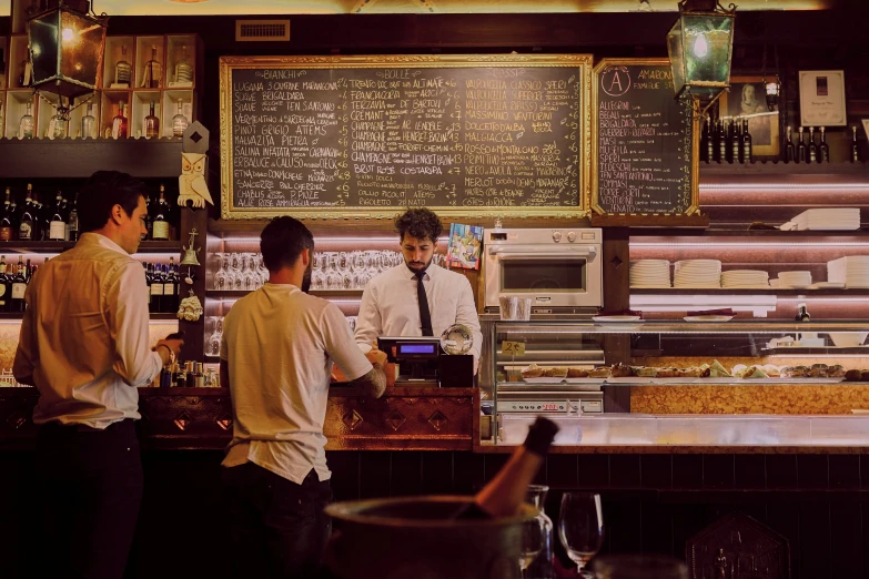 three men at the bar of a restaurant with menus on the back