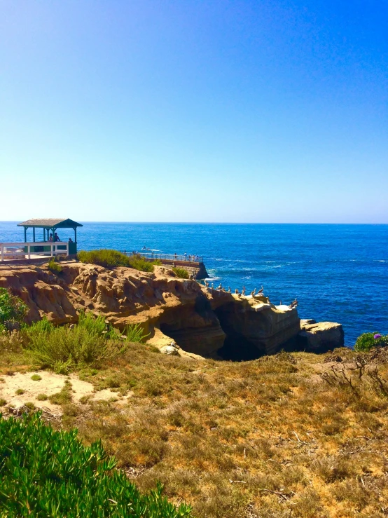 an empty bench is sitting on the cliffs by the water