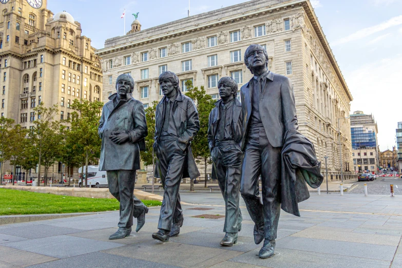 a statue of three men walking by some buildings