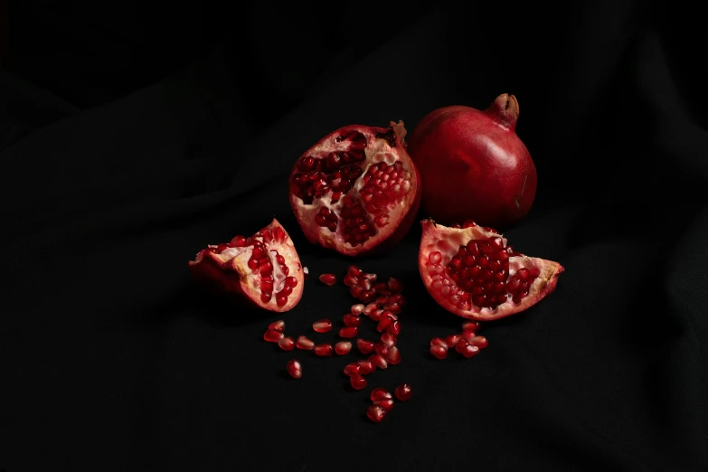 pomegranates are scattered on a black surface