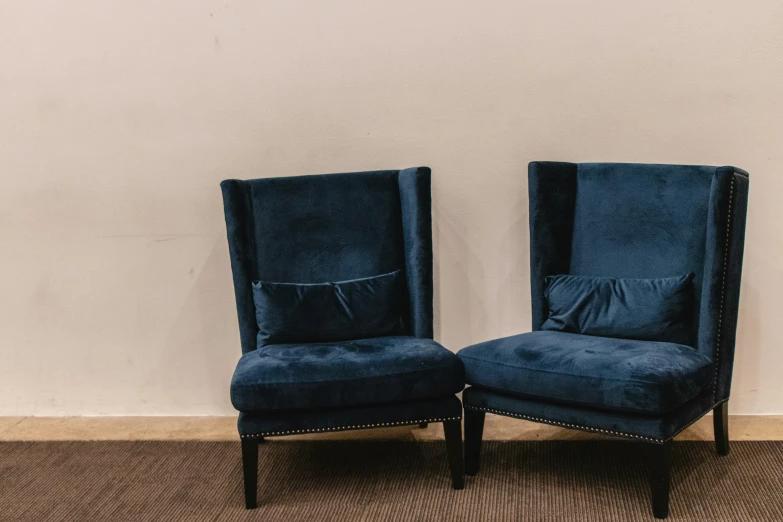 a pair of blue chairs facing each other on a brown carpet