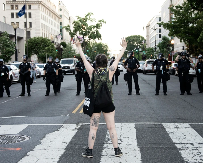 a woman standing on the side of a road with police behind her