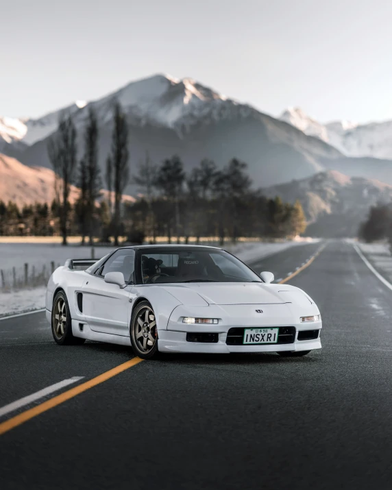 the front of a white sport car stopped on the side of a road