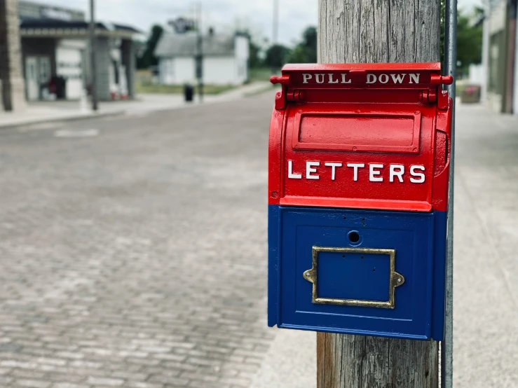 a red and blue post has an old style mail box attached to it