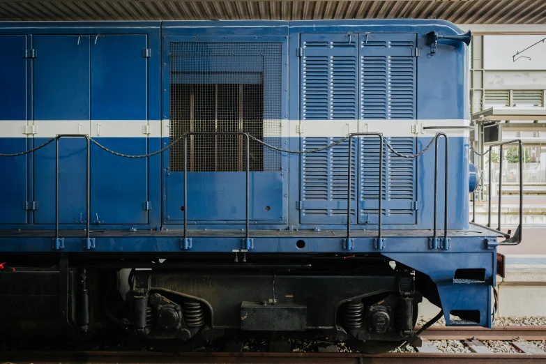 a blue train that is next to some tracks