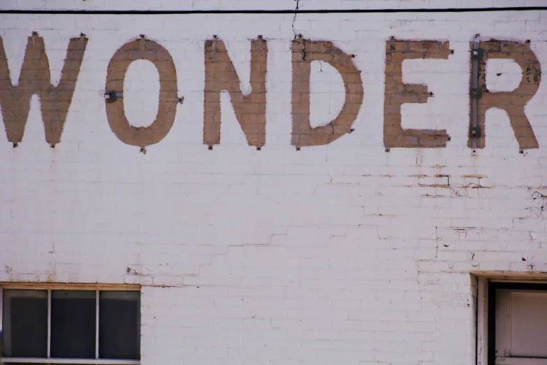 an old sign on the side of a building saying wonders