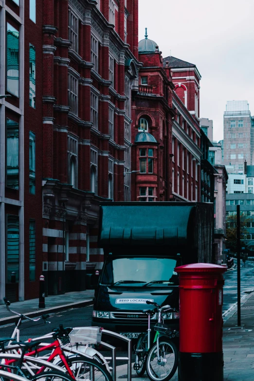 there is a red trash can and two bicycles by the street