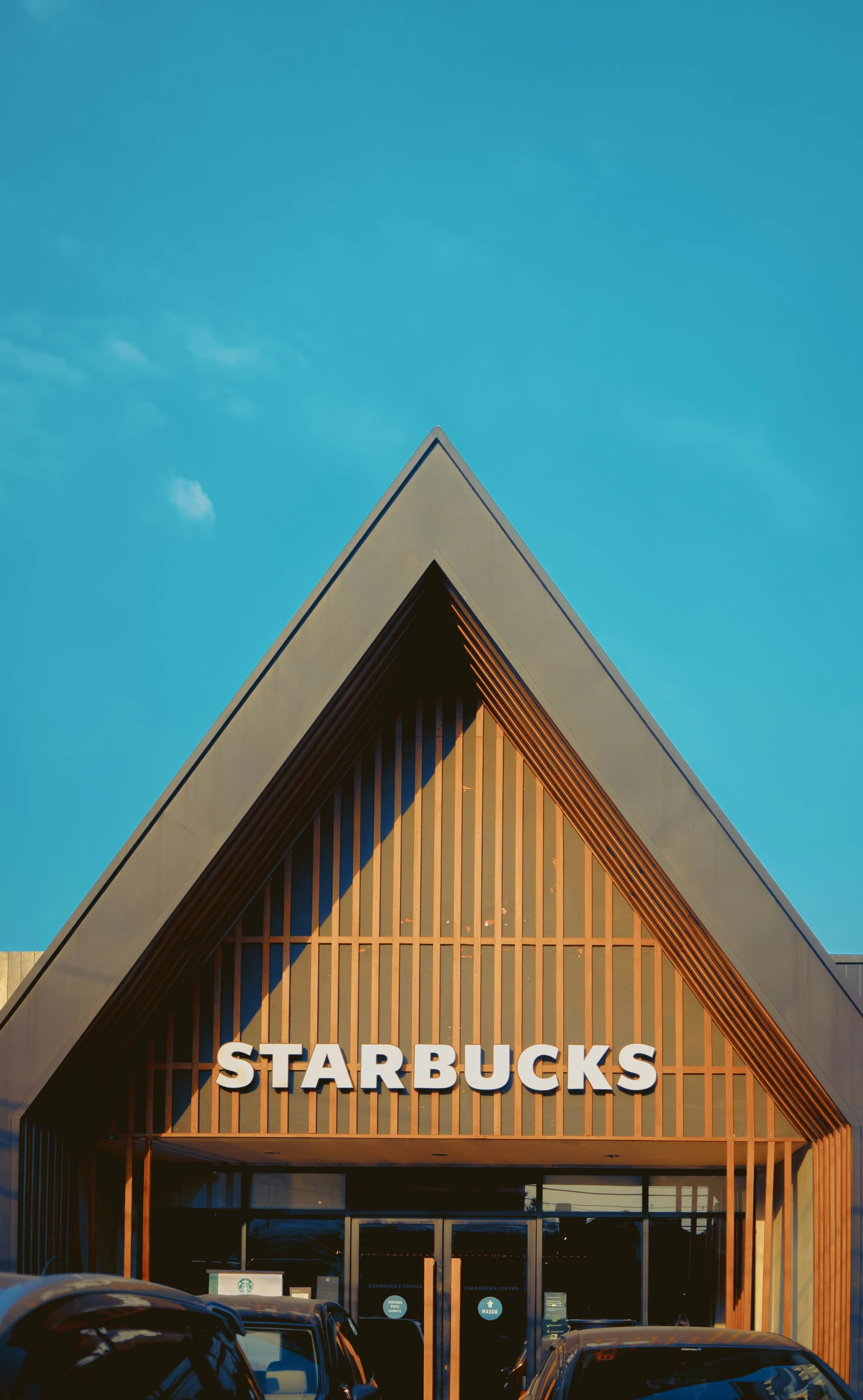 two black cars parked outside a store with a starbuck's logo on it