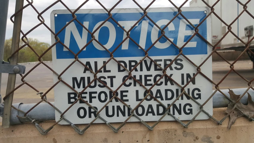 the sign is attached to a gate next to a parking lot