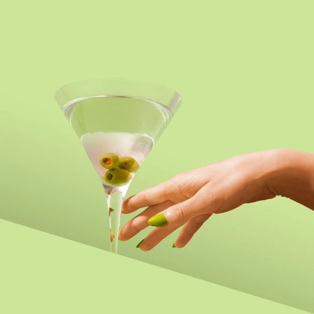 a hand holding a glass with olives in it