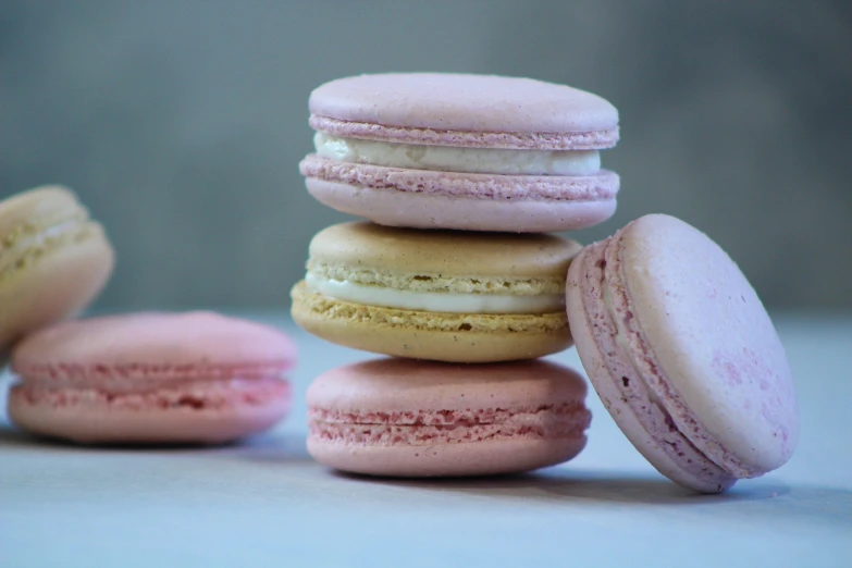 several pink macaroons, one half with a glaze, the other half stacked