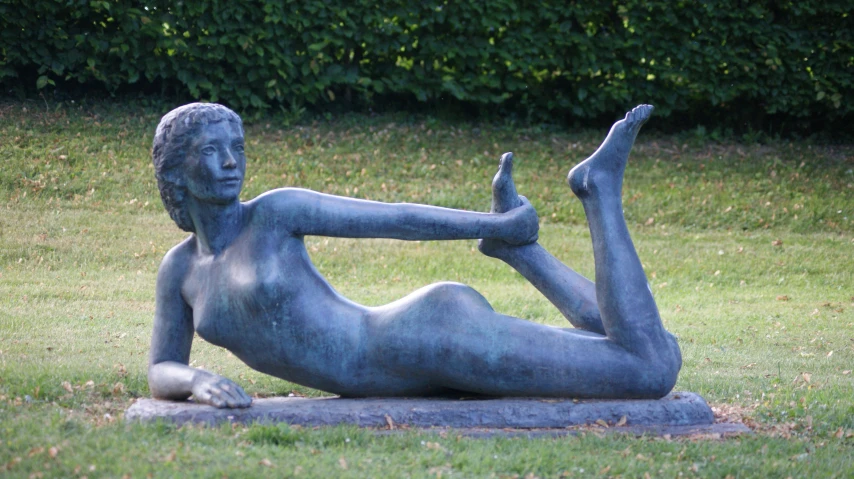 a statue of a  woman lying on her stomach in a grassy area