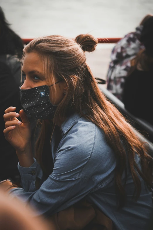 a woman looks down at her face as she holds up an oversize mask over her mouth