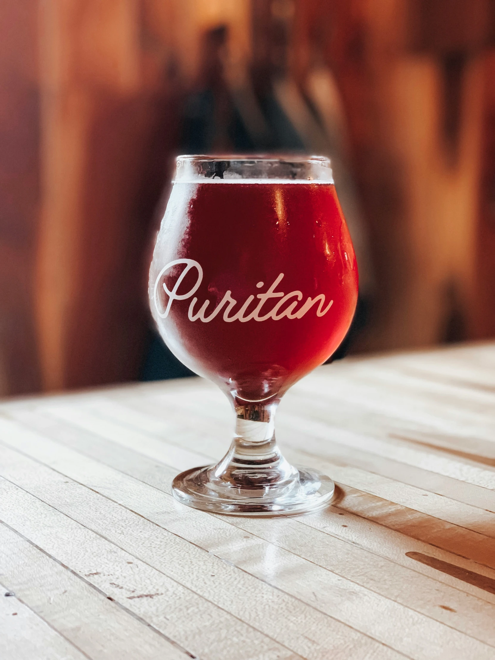 there is a glass of beer that reads puritan