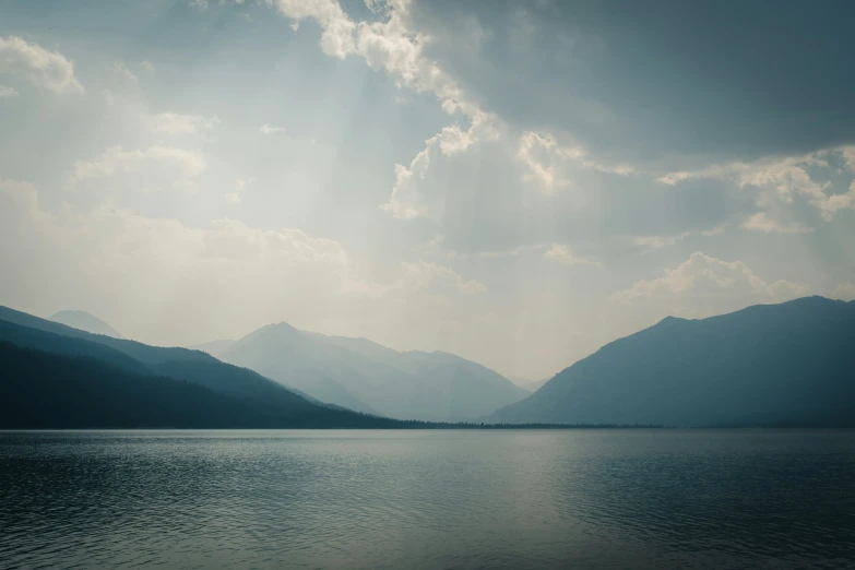 a river with mountain ranges and clouds above