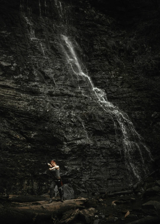 two people stand on a rock under a waterfall