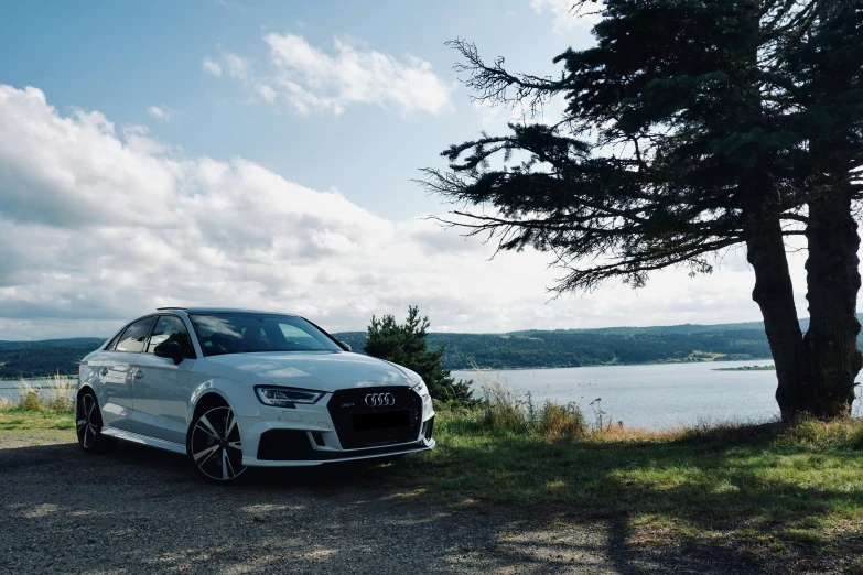 a white car parked next to some trees near the water