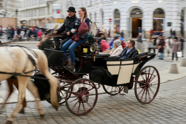 people are in a horse drawn carriage on the street