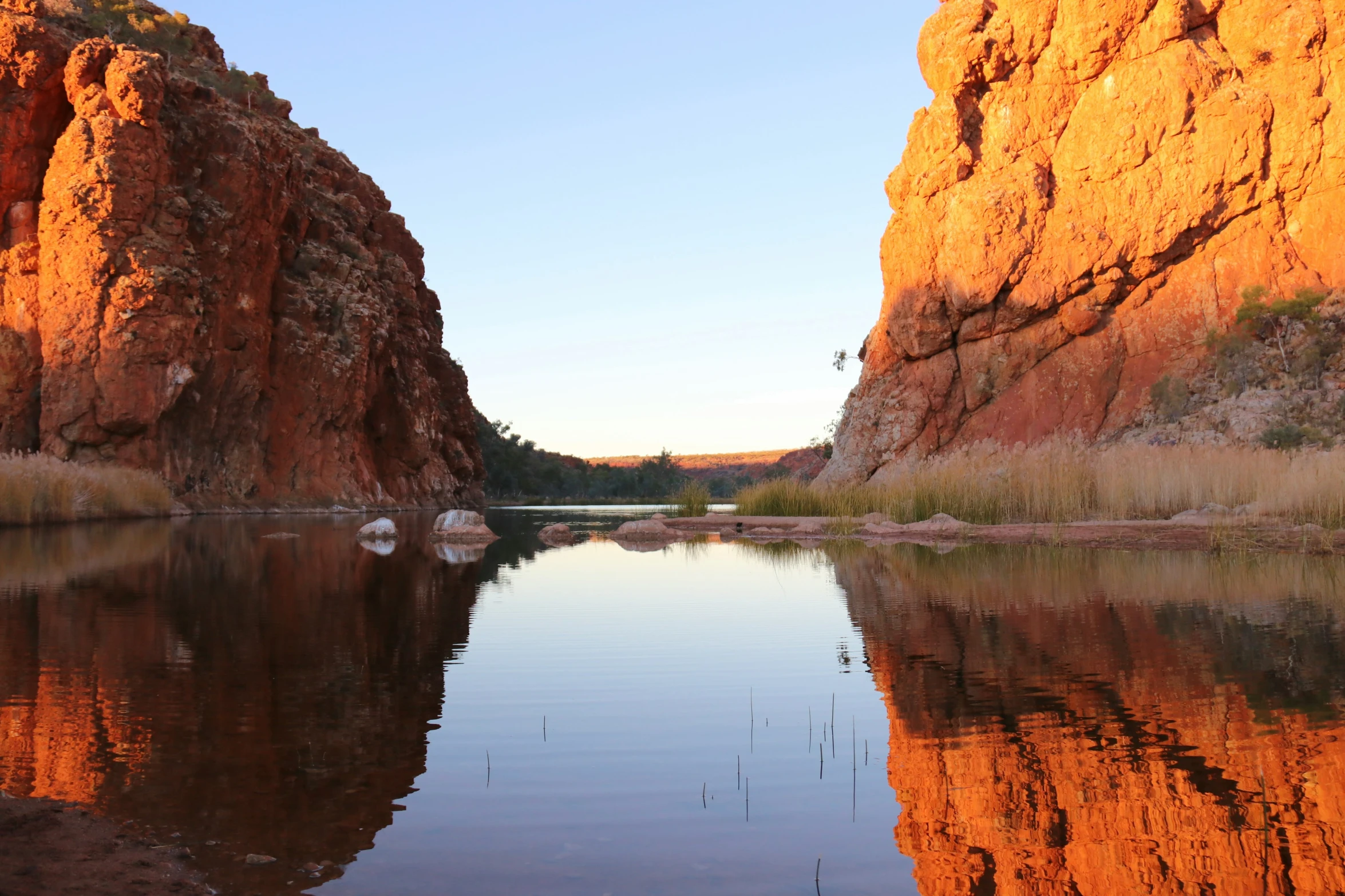 a calm river with rocky shore and a cliff face