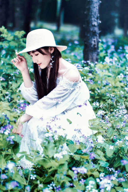 a woman kneeling in the middle of a field of flowers