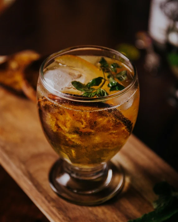 a glass filled with ice sitting on top of a wooden tray