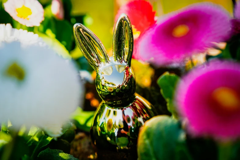 a decorative glass rabbit is sitting among flowers