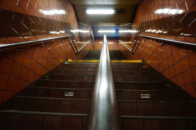 a long stairway has metal railings and dark walls