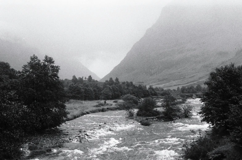 black and white pograph of a stream with mountains in the background