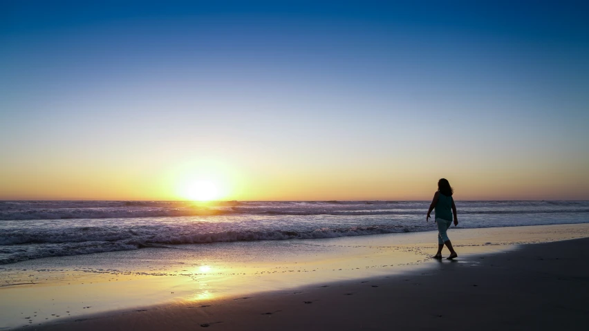 a person walking on a beach with a frisbee in their hand