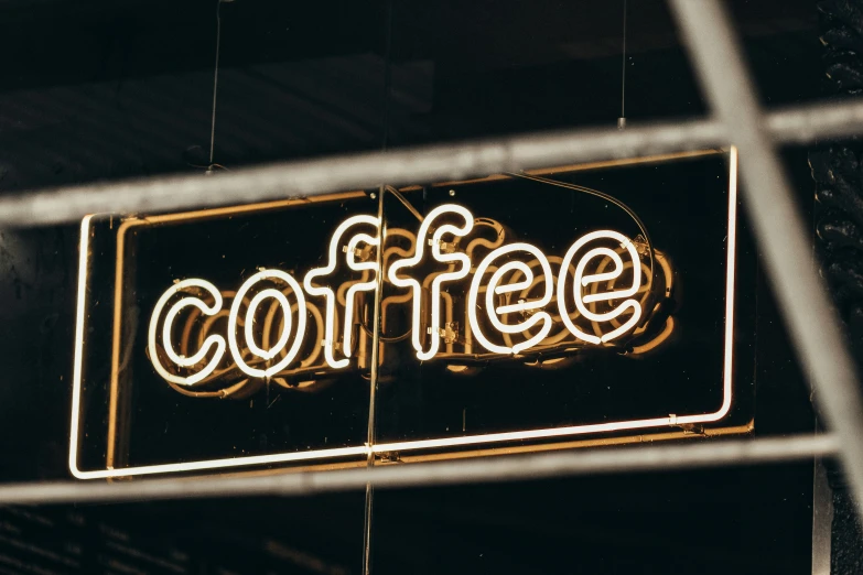 a coffee sign is illuminated against a window