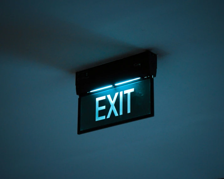 green exit sign hanging on the wall in a room