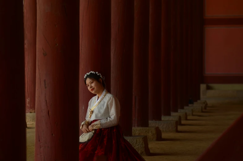 a woman in an asian fashion posing by a pillar