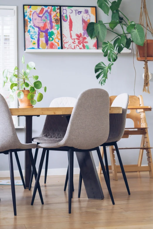 four chairs with plant on a table in front of two pictures